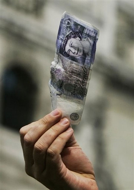 Ahead of the G20 summit, a lone protester holds up a banknote of 20 British pounds as he delivers a speech on the financial issues, in central London's City financial district, Tuesday March 31, 2009.
